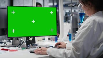 laboratorio técnico a escritorio mecanografía en verde pantalla ordenador personal teclado, mirando a molecular modelo, haciendo investigación tareas. mujer utilizando bioingeniería programa en Bosquejo computadora en médico laboratorio, cámara si video