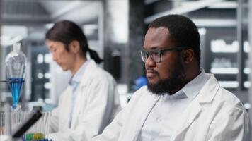 Stressed laboratory scientist using computer monitor, processing DNA patient data for clinical research. Anxious lab specialist looking at genetic analysis diagnostics on PC, camera B video