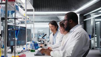 Senior researcher records observations from coworkers using microscope to evaluate cellular structures. Man taking notes of medical tissue observation through magnification tool, camera A video