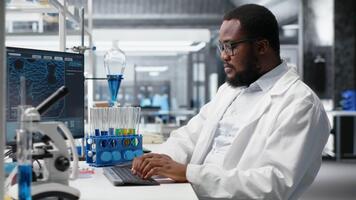 científico mecanografía en teclado, utilizando computadora programa para adn datos análisis en laboratorio conducción tratamiento descubrimiento. experto utilizando bioinformática software en ordenador personal en estéril laboratorio, cámara si video