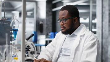 laboratorio lavoratore strabismo occhi a computer tenere sotto controllo, lottando per capire dna dati. africano americano laboratorio esperto incapace per credere occhi mentre guardare a genetico analisi diagnostica, telecamera B video