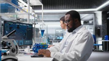 betonade laboratorium forskare använder sig av dator övervaka, bearbetning dna patient data för klinisk forskning. angelägen labb specialist ser på genetisk analys diagnostik på pc, kamera en video