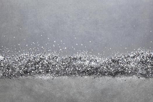 Sparkling silver dust spreads across a grey surface photo