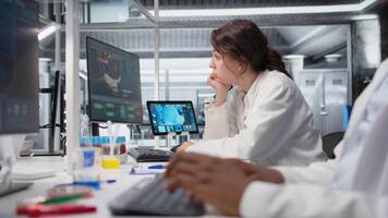aburrido médico laboratorio técnico utilizando computadora solicitud para adn datos análisis. perezoso investigación instalaciones trabajador utilizando bioinformática genómica programa en ordenador personal en alto tecnología laboratorio, cámara un video