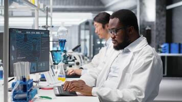 laboratorio bioinformática científico evalúa genético marcadores utilizando ordenador personal, analizando muestra propiedades. hombre estudios adn hebra cartografía y químico solución componentes utilizando programa en computadora, cámara si video