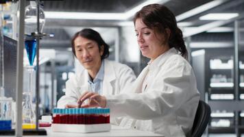 mayor laboratorio experto y aprendiz analizando lote de sangre muestras para enfermedad investigación clínico pruebas. laboratorio gerente y interno haciendo investigación en optimista fluido viales para pruebas, cámara si video