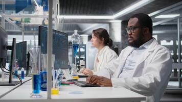 Scientist in laboratory interprets clinical blood values on computer monitor during study. Research facility worker doing sanguine fluid analysis, looking at healthcare insights report on PC, camera A video