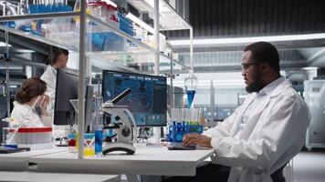 científico mecanografía en teclado, utilizando computadora programa para adn datos análisis en laboratorio conducción tratamiento descubrimiento. experto utilizando bioinformática software en ordenador personal en estéril laboratorio, cámara un video