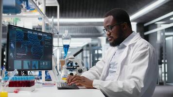laboratorium arbetstagare vindögd ögon på dator övervaka, kämpar till förstå dna data. afrikansk amerikan labb expert- oförmögen till tro ögon medan ser på genetisk analys diagnostik, kamera en video