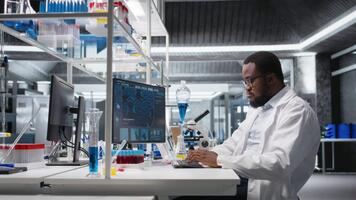 laboratorio especialista haciendo genética estudiar utilizando clínico equipo, quitando los anteojos, comprobación análisis resultados en computadora. hombre utilizando científico engranaje a banco de trabajo, haciendo complejo experimentos, cámara un video