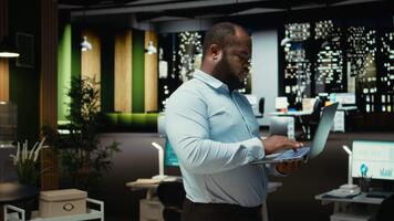 zwart vent onderzoeken gearchiveerd documenten voordat transcriberen Aan pc notitieboekje, notities maken en extraheren de hoofd points van rapporten Aan laptop. analist documenteren na uren laat Bij nacht. camera a. video