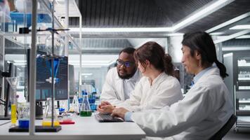 multirracial laboratório técnicos às pc escrivaninha olhando às 3d molecular modelo. diverso nanotecnologia pesquisadores usando Bioengenharia programa em pc dentro médico laboratório exibindo dna dados, Câmera uma video