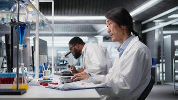 laboratorium tekniker använder sig av dator Ansökan för dna data analys, håller på med forskning in i mänsklig hälsa. asiatisk labb ingenjör använder sig av bioinformatik genomik programvara på pc, kamera en video