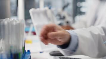 vicino su di laboratorio tecnico fa pipettaggio procedura con sostanze chimiche, miscelazione soluzioni per reazione test. clinico microbiologo usi pipetta per trasferimento liquido in test tubo, tremante per miscela video