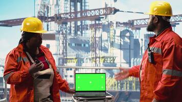Isolated screen laptop used by drilling rig crew colleagues holding radio device to monitor systems. Engineering team on offshore platform deck using walkie talkie and chroma key notebook, camera B video