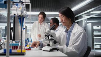 Sénior microscopiste examiner microscope verre faire glisser dans laboratoire à vue cellules. asiatique recherche établissement employé chèques échantillon faire glisser avant imagerie processus en utilisant optique appareil, caméra une video