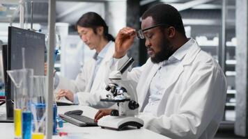 clinique microbiologiste dans laboratoire en utilisant microscope pour pathologie recherche, à la recherche à moléculaire données. recherche établissement professionnel en utilisant optique dispositif équipement à examiner tester des spécimens, caméra b video