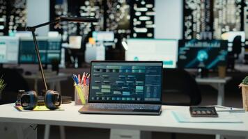 bärbar dator på en arbetsstation i tömma mörk kontor sent på natt, visa upp data och infographics för framtida rapporterar. prestanda metrik och prognostisering grafer reflektera företag administrering. video