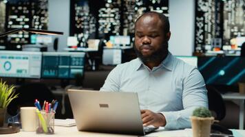 negro persona corrección de pruebas y hecho comprobación financiero números, revisando archivado archivos después horas en el estrategia habitación. evaluando datos en informes, investigando y organizando agenda. cámara b. video