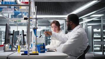 squadra di analitico chimici opera insieme, utilizzando laboratorio cristalleria con soluzioni. lavoro di gruppo scienziati raccolta campione tubi con chimico fluido Usato per esperimenti, telecamera un' video