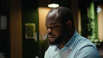 afrikansk amerikan kille skriver information på bärbar dator och kontroll rapporter, korrekturläsning och granskning data för en ny företag mål eller mål. företag förvaltning efter timmar. kamera b. video