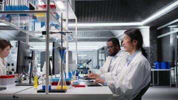 sonriente asiático laboratorio investigador utilizando computadora a proceso adn paciente datos para clínico investigación. optimista laboratorio experto satisfecho por laboratorio genético análisis diagnósticos resultados en ordenador personal, cámara un video