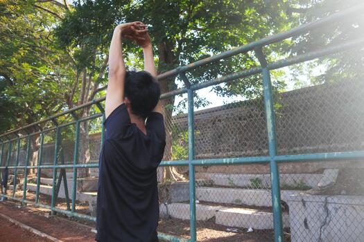 A man is stretching his arm in front of a fence. Concept of determination and focus as the man works, on his, flexibility photo
