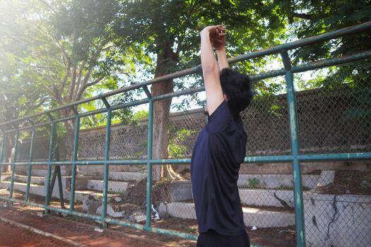 A man is stretching his arm in front of a fence. Concept of determination and focus as the man, works on, his flexibility photo