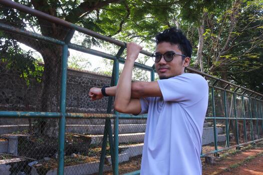 A man is stretching his arm in front of a fence. Concept of determination and, focus as the man works on his flexibility photo