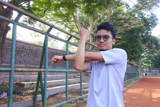 A man is stretching his arm in front of a fence. Concept of determination and focus, as the man works on his flexibility photo