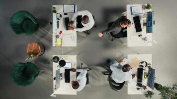 Top down view of employees reviewing charts and diagrams during briefing. Corporate team leads discussions on planning, documentation and report writing to enhance business intel. Camera A. video
