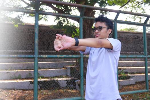A man is stretching his arm in front of a fence. Concept of determination and focus as the, man works on his flexibility, photo