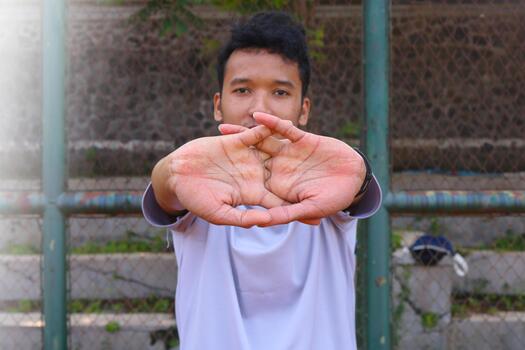 A man is stretching his arm in front of a fence. Concept of determination and focus as the man works, on his flexibility photo