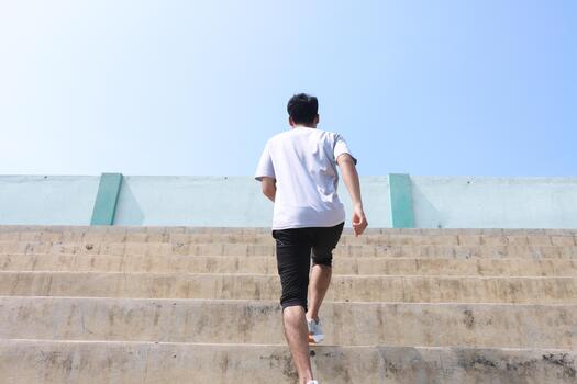 A man is running up a set of stairs. Concept of determination and perseverance as the man pushes himself to reach the top of the, steps. The man's focused expression photo