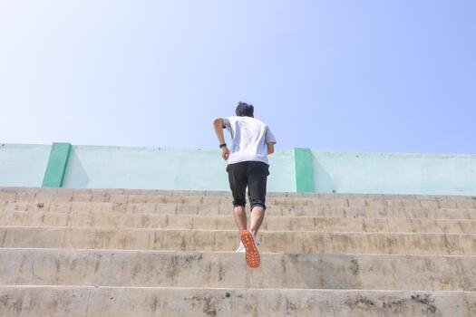 A man is running up a set of stairs. Concept of determination and perseverance as the man pushes himself to reach the top of the steps. The, man's focused expression. photo