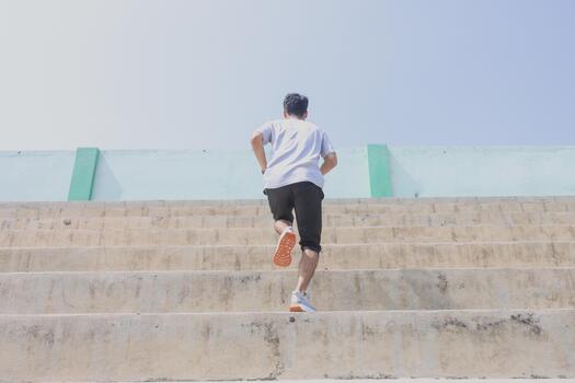 A man is running up a set of stairs. Concept of determination and perseverance as the man pushes himself to reach the top of the steps. The man's focused, expression. photo