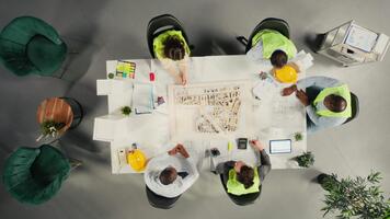 parte superior abajo ver enfocar en de diverso colegas consultante en un Maestro plan para urbano desarrollo. propiedad desarrolladores revisión arquitectónico software y diseños a lograr real inmuebles crecimiento. cámara una. video