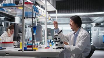 Sénior laboratoire ingénieur inspecter spécimen faire glisser pour microscopie étude en utilisant optique appareil. médical laboratoire technicien révision cytologie faire glisser pour clinique essai procédure, caméra une video