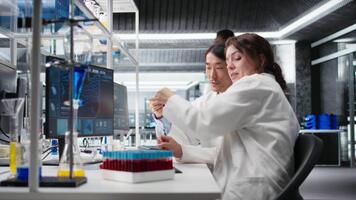 mayor laboratorio experto y aprendiz analizando lote de sangre muestras para enfermedad investigación clínico pruebas. laboratorio gerente y interno haciendo investigación en optimista fluido viales para pruebas, cámara un video