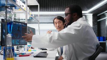 gemischtrassig Ingenieure mit wissenschaftlich Ausrüstung im Forschung Einrichtung benutzt zum Komplex Experimente. vielfältig Mannschaft von Wissenschaftler im hoch Technik Labor tun Genetik Forschung mit Labor Ausrüstung, Kamera ein video