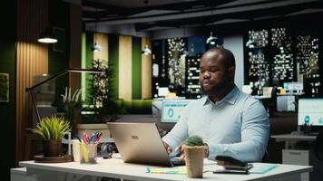 porträtt av manlig arbetstagare nedsänkt i läsning e-postmeddelanden och forska data för en multinationell företag, arbetssätt efter timmar i en mörk kontor. fokusera på mål för utveckling. kamera a. video