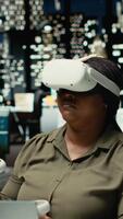 vertikal svart allmän direktör anställer ai gadgetar med virtuell verklighet i de kontor, arbetssätt hård efter timmar med vr headsetet till säkerställa faktum kontroll och prognostisering projektioner. strategi rum. kamera b. video