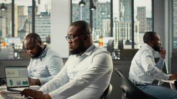 colegas compartiendo informes y visual datos en computadora en oficina. trabajo equipo realiza riesgo evaluación, estrategia planificación y datos visualización a garantizar fuerte actuación y progreso. cámara b. video