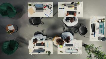 Tempo lapso topo baixa Visão do diverso colegas trabalhando dentro escritório, concentrando em projeto planejamento, desempenho Métricas e relatório compartilhamento. o negócio pessoas Reveja dados para previsão. Câmera uma. video