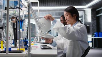 laboratorio professionale esamina test tubo campione sotto controllato illuminazione per trasparenza e consistenza. scienziato usi lampada illuminazione per osservare liquido proprietà e individuare impurità, telecamera un' video