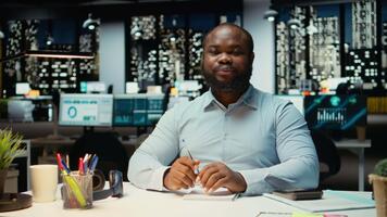 africano americano maschio consulente unendo un' ragnatela chiamata su computer portatile, impegnato nel discussione dopo ore. professionale uomo interagendo con azionisti, adattabilità nel networking sessione. telecamera un. video