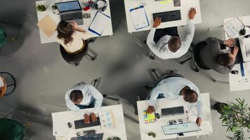Top down view zoom in of business people gathered around laptops working on project tasks for development. Office environment promotes synergy, teamwork and insight through analytics. Camera A. video
