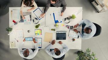 topp ner se zoom ut av kollegor utbyte idéer under företag möte. professionell team undersöker finansiell data, mål och företag intel till justera mål för framsteg. kamera b. video