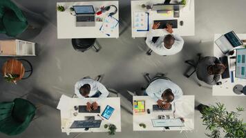 topo baixa Visão ampliação dentro do colegas verificação arquivado arquivos dentro ambiente de trabalho, revendo gráficos e análise. empregados discutir projeto progresso, relatório escrevendo e dados visualização. Câmera uma. video