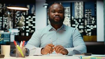 africano americano maschio consulente unendo un' ragnatela chiamata su computer portatile, impegnato nel discussione dopo ore. professionale uomo interagendo con azionisti, adattabilità nel networking sessione. telecamera b. video